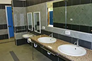 Camping Arrighi - Innenraum des Sanitärgebäudes mit Waschbecken und Spiegeln
