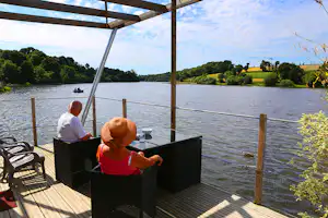 Camping Au Bocage du Lac - Camper auf der Veranda vom Mobilheim auf dem Campingplatz am See Étang de Jugon