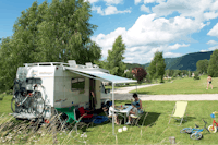 Camping Au Joyeux Reveil - Camper sitzen vor dem Wohnmobil im Schatten der Markise