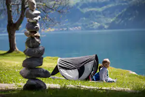 Camp au Lac -Kinder sitzen am Ufer des Sees vor einem Mini Sonnenschutz