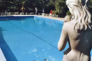 Camping Aurelia Club - Swimmingpool auf dem Campingplatz mit Sitzgelegenheiten am Rand und einer Statue im Vordergrund