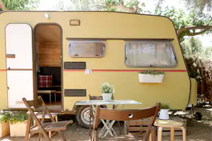 Camping Azahar - Wohnwagen im Schatten mit Tischen und Stühlen