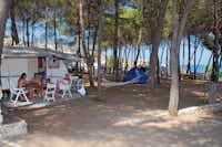 Camping Baia San Nicola - Wohnwagen mit davor sitzender Familie zwischen Bäumen