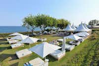 Camping Barcelona  - Bar und Liegen mit Sonnenschirmen auf grüner Wiese vom Campingplatz mit Blick auf das Mittelmeer