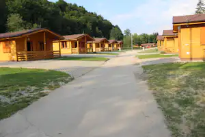 Camping Belá - Strasse auf dem Campingplatz mit mietbaren Holzhütten mit überdachten Veranden zu beiden Seiten