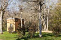 Slow Village Périgord - Blick auf eine Tinyhouse-Mietunterkunft im Grünen zwischen Bäumen