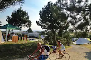 Camping Bel Sito - radelnde Camper aif dem Campingplatz mit Zelten und Chalets im Hintergrund