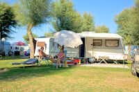 Camping Bellamare - Camper sitzen vor ihrem Wohnwagen auf dem Campingplatz