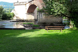 Camping Bellerive - Bank auf grüner Wiese mit Blick auf die Brücke am Flluss
