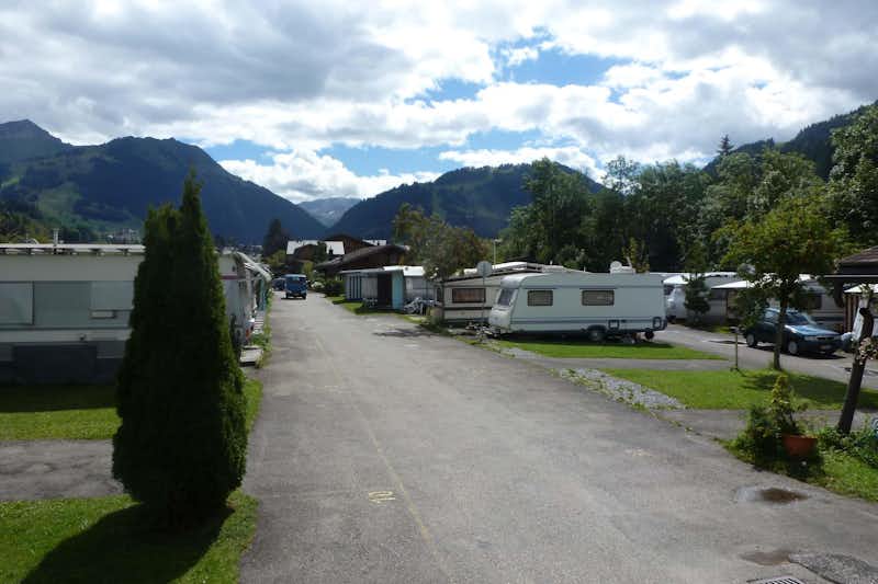 Camping Bellerive - Strasse auf dem Campingplatz mit Stellplätzen an beiden Seiten, auf denen Wohnwagen und Wohnmobile stehen