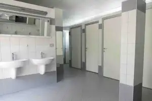 Badezimmer im Campingbereich mit mehreren Waschbecken, Spiegeln und Duschkabinen mit Türen.