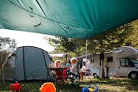 Camping Bled -  Camper sitzen vor dem Wohnmobil im Schatten der Markise