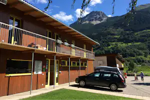 Camping Boomerang - zweistöckiges Gebäude auf dem Campingplatz mit Parkplätzen davor