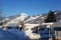 Camping Brixen im Thale - Wohnwagen auf Stellplätzen im Winter mit den Bergen im Hintergrund