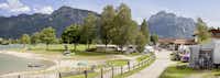 Camping Brunnen - Stellplätze auf dem Campingplatz im Schatten unter Bäumen am See bei Füssen mit Blick auf die Allgäuer Alpen