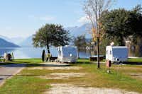 Camping Brunner am See - zwei Wohnwagen auf dem Campingplatz mit dem See und den Bergen im Hintergrund