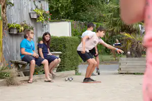 Kinder spielen auf dem Campingplatz im Garten, mit Sitzbank, Holzstufen und Kugeln auf dem Kiesweg.