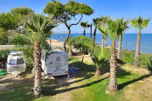 Camping & Bungalows Estanyet - Wohnwagen- und Wohnmobilstellplätze zwischen Bäumen neben dem Meer