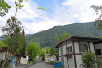 Camping Buosingen - Bungalows und Mobilheime an einer Strasse auf dem Campingplatz mit Paraglider in der Luft
