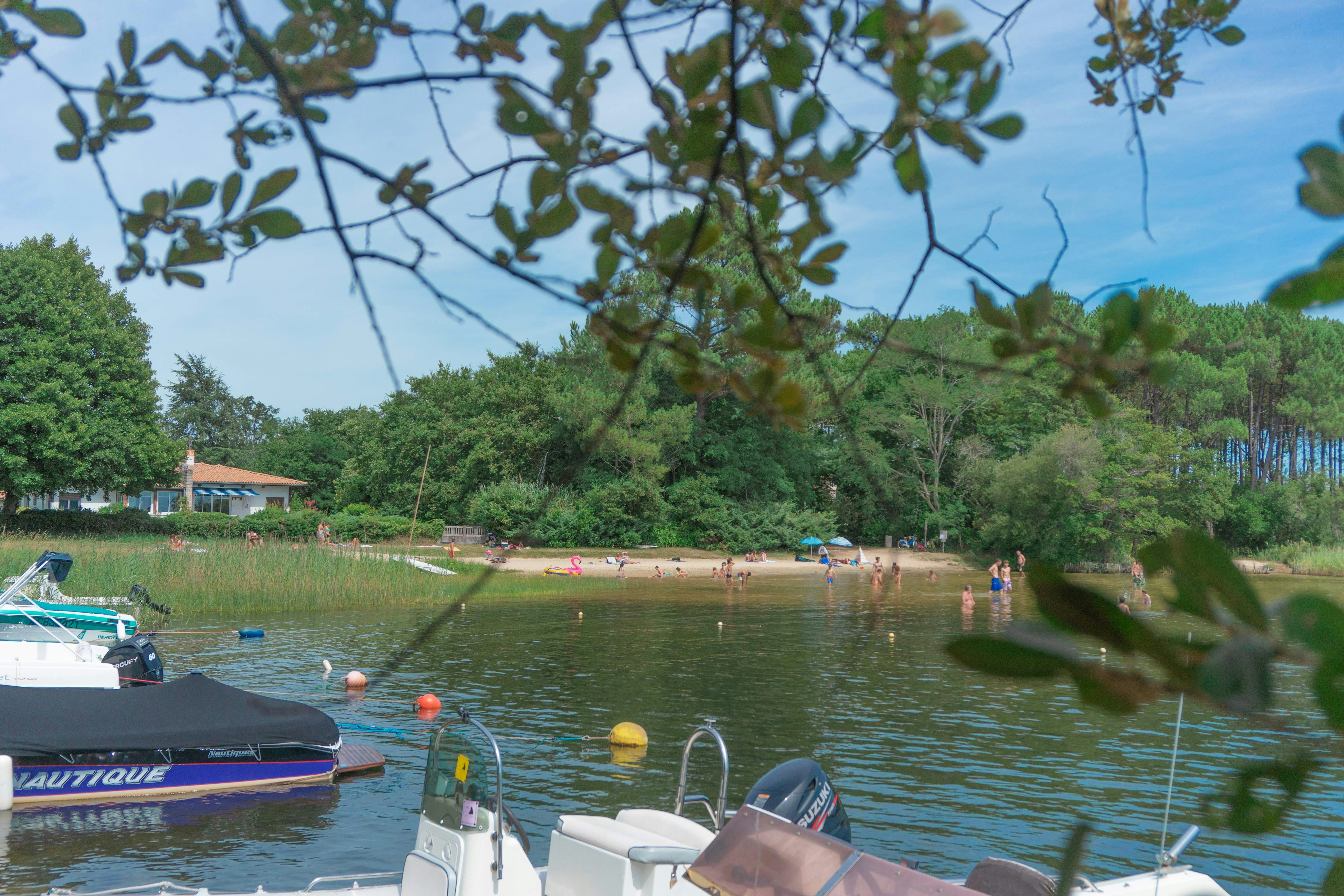 Bootssteg am See mit geparkten Motorbooten, Ruderbooten und Blick auf Ufer mit Bäumen und Häusern.