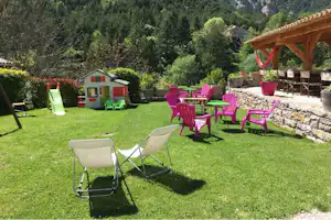 Camping Calme et Nature - WIese auf dem Campingplatz beim Imbiss mit Sitzgelegenheiten im Freien und Spielhütte für Kinder