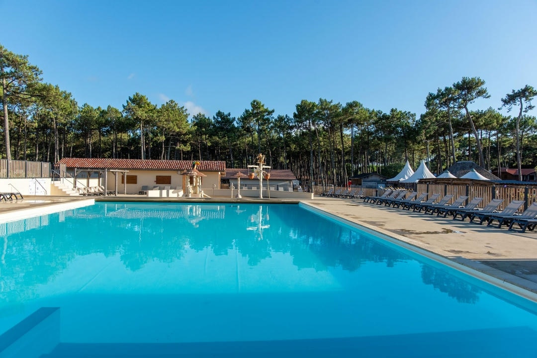 Camping Campéole Les Tourterelles  Camping Club Les Tourterelles  - Pool im Freien mit Liegestühlen und Sonnenschirmen