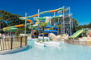 Wasserrutschen am Campingplatz über einem Pool, mit bunten Leitern, Spielbereich und Zaun aus Holzlatten.