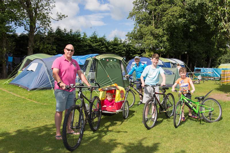Camping Caseys - Camper mit Fahrrädern vor Zelten