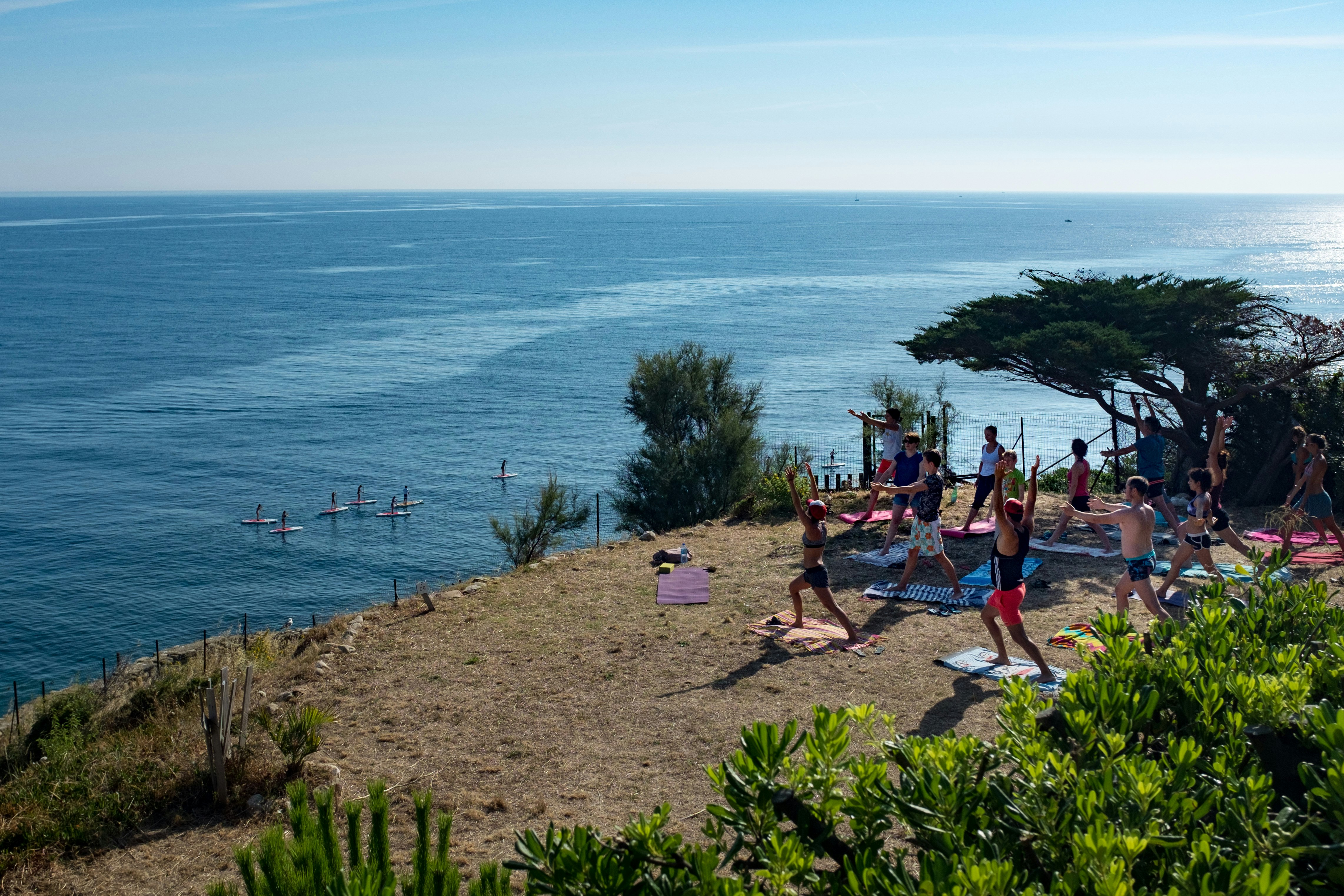 Camping Castels Les Criques de Porteils -  Gäste entspannen beim Yoga im Schatten am Strand mit Blick auf das Mittlmeer
