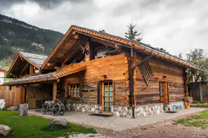 Camping Catinaccio Rosengarten - Holzhütte in bergiger Landschaft mit Fahrrädern vor dem Eingang