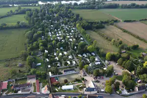 Luftaufnahme eines Campingplatzes mit Wohnwagen und Zelten, Wegen, Bäumen und Feldern rundherum.