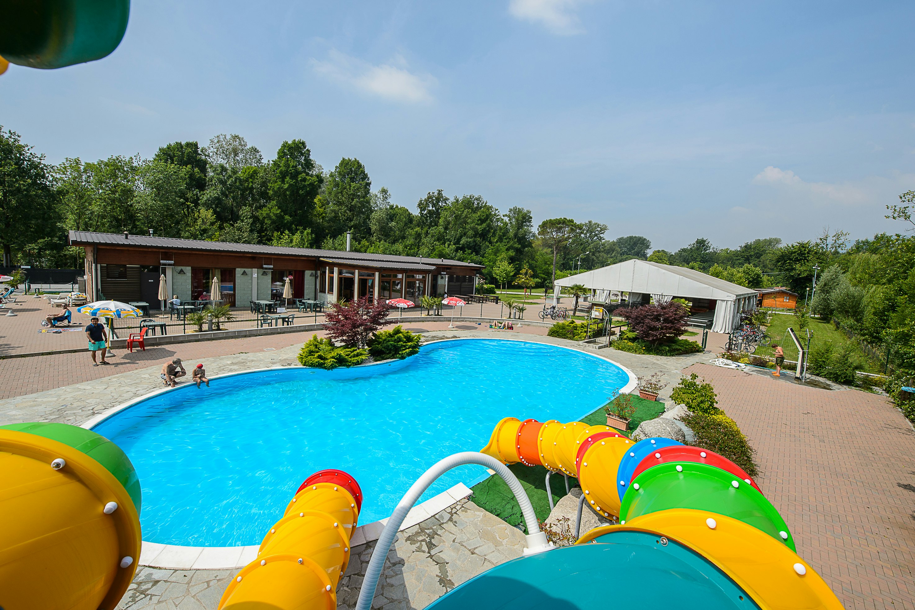 Camping Class -Wasserrutsche vom Poolbereich im Vordergrund,  Restaurant mit Terrasse im Hintergrund