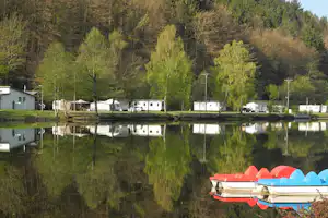 Camping Clausensee - Blick vom See auf den Wohnwagen- und Zeltstellplatz und Mobilheime vom Campingplatz