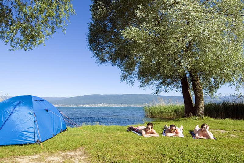 Camping Communal Le Chablais - Camper auf Zeltwiese mit dem Neuenburgersee im Hintergrund