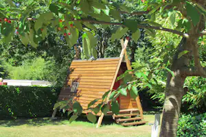 Holzhütte im Garten mit Holztreppe, Bank und umgebenden Bäumen, Blick durch Blätter mit roten Früchten.