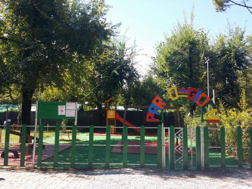 Bunter Spielplatz am Campingplatz mit Holz-Zäunen, Kletterelementen und Bäumen im Hintergrund.