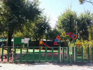 Bunter Spielplatz am Campingplatz mit Holz-Zäunen, Kletterelementen und Bäumen im Hintergrund.