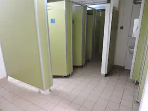 Flur in einem Campinghaus mit grünen Türen, weißen Wänden und Fliesenboden, Blick in den Korridor.