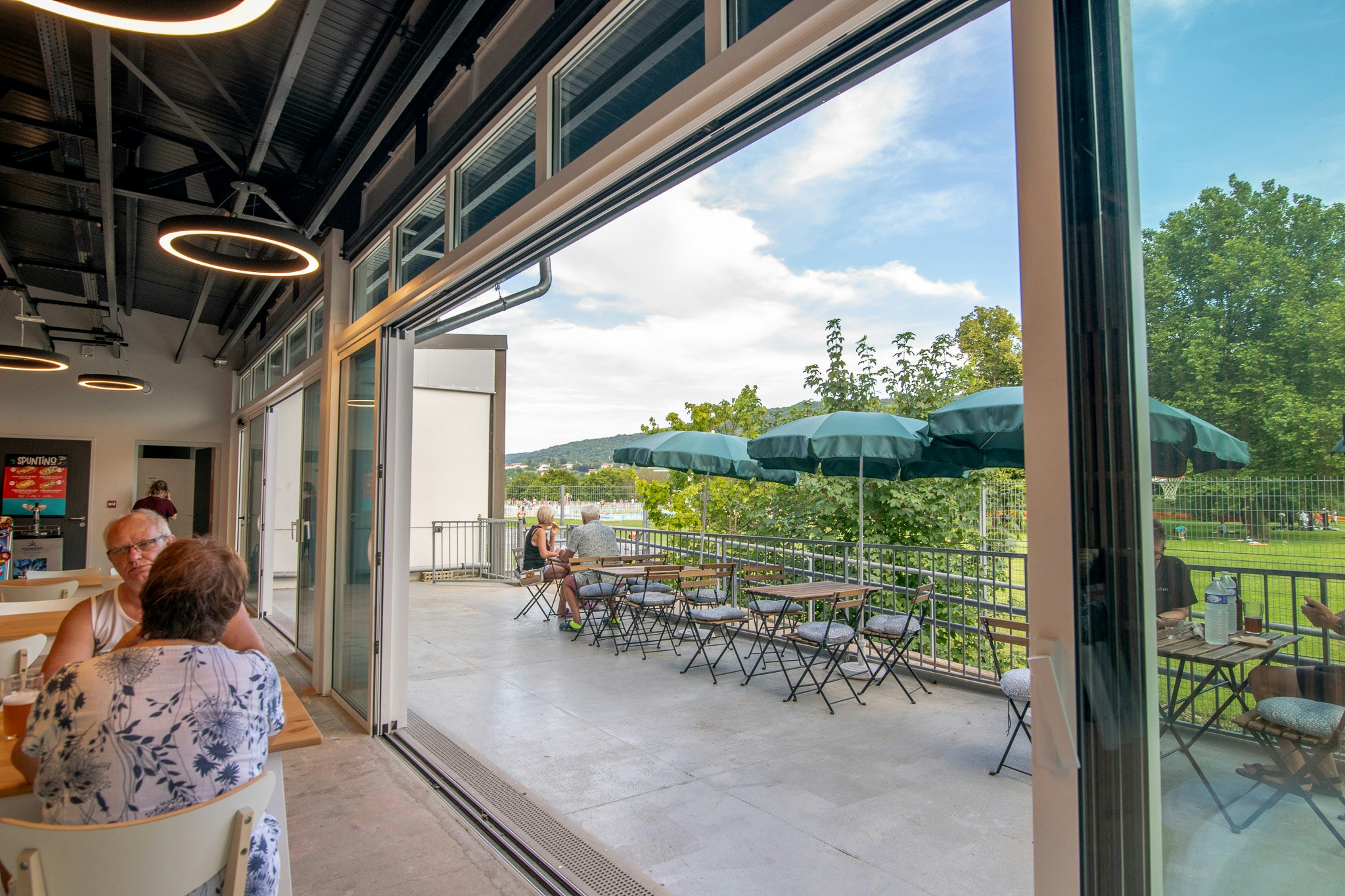 Onlycamp Camping de Besançon - Blick nach draußen auf die Terrasse aus dem Café