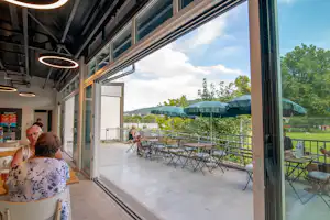 Onlycamp Camping de Besançon - Blick nach draußen auf die Terrasse aus dem Café