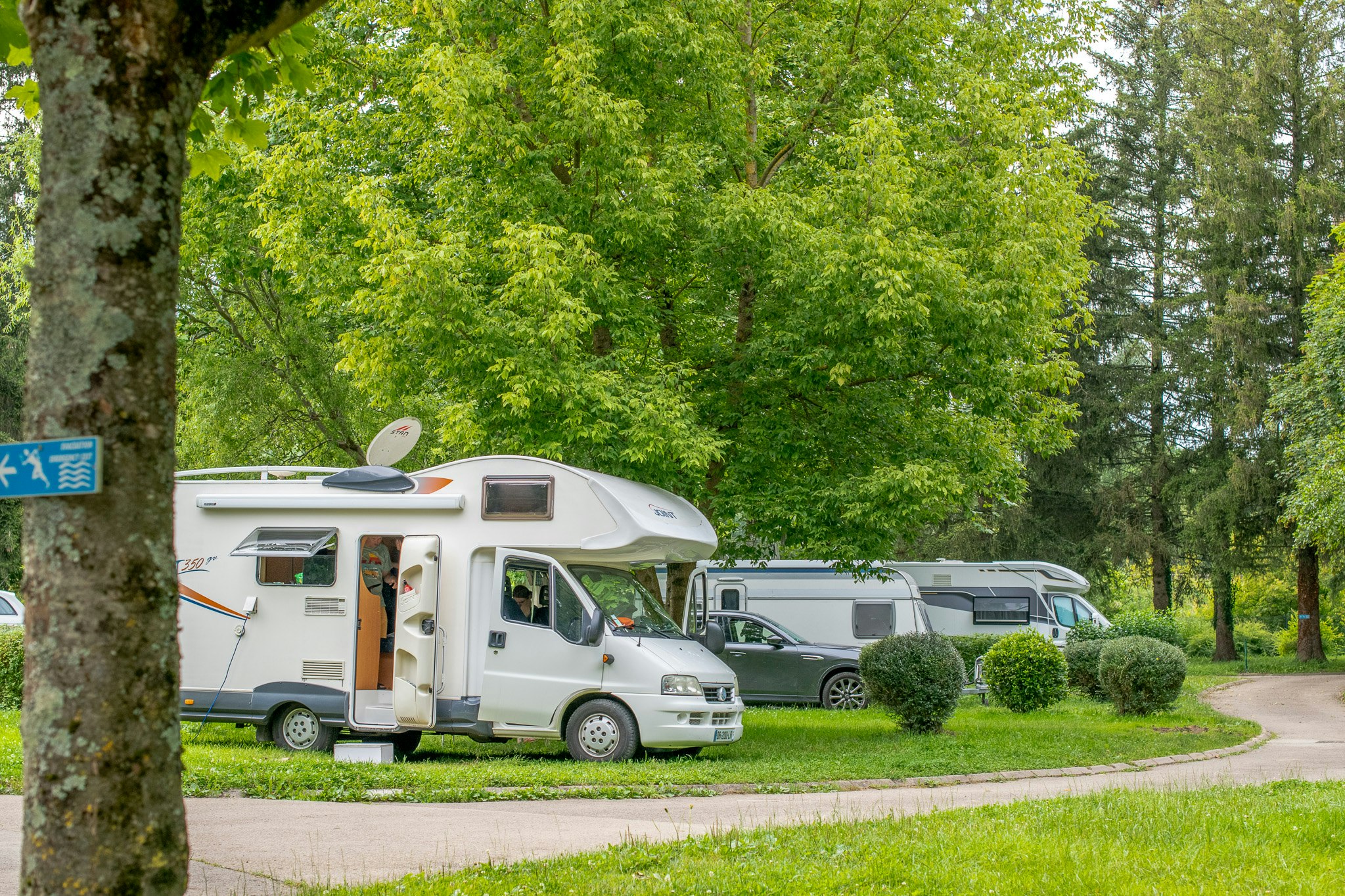 Onlycamp Camping de Besançon Camping de Besançon La Plage - Wohnmobil- und Wohnwagenstellplätze auf der Wiese im Schatten der Bäume