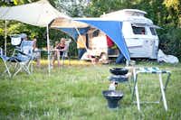 Camping De Bron - Camper sitzen vor dem Wohnmobil im Schatten der Markise