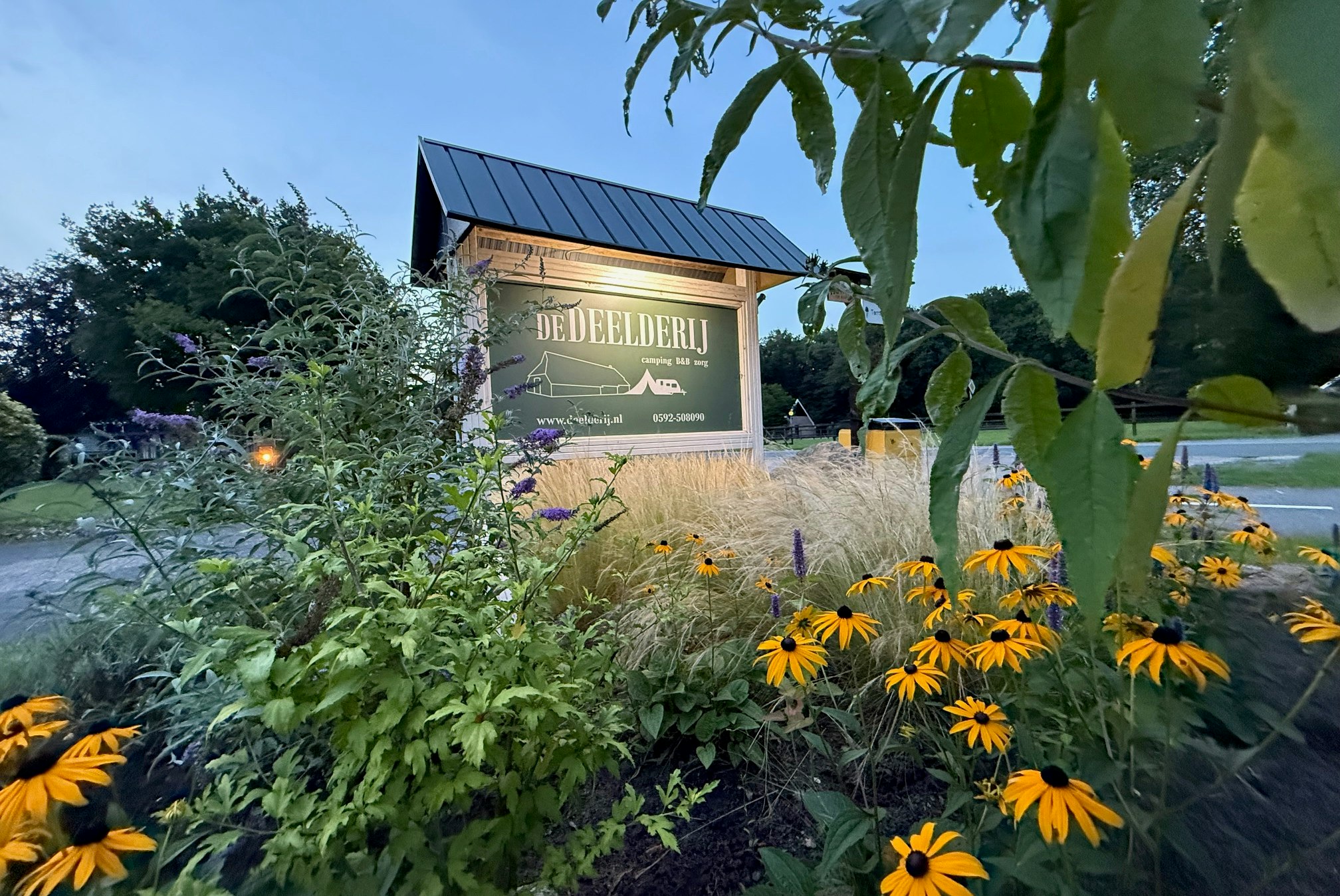 Camping De Deelderij - Blumen und Eingangsschild am Campingplatz