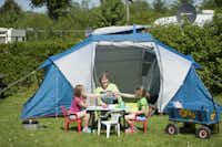 Camping De Gavers Wohnmobil  -  Camper Familie am Zelt auf dem Wohnwagen- und Zeltstellplatz auf grüner Wiese