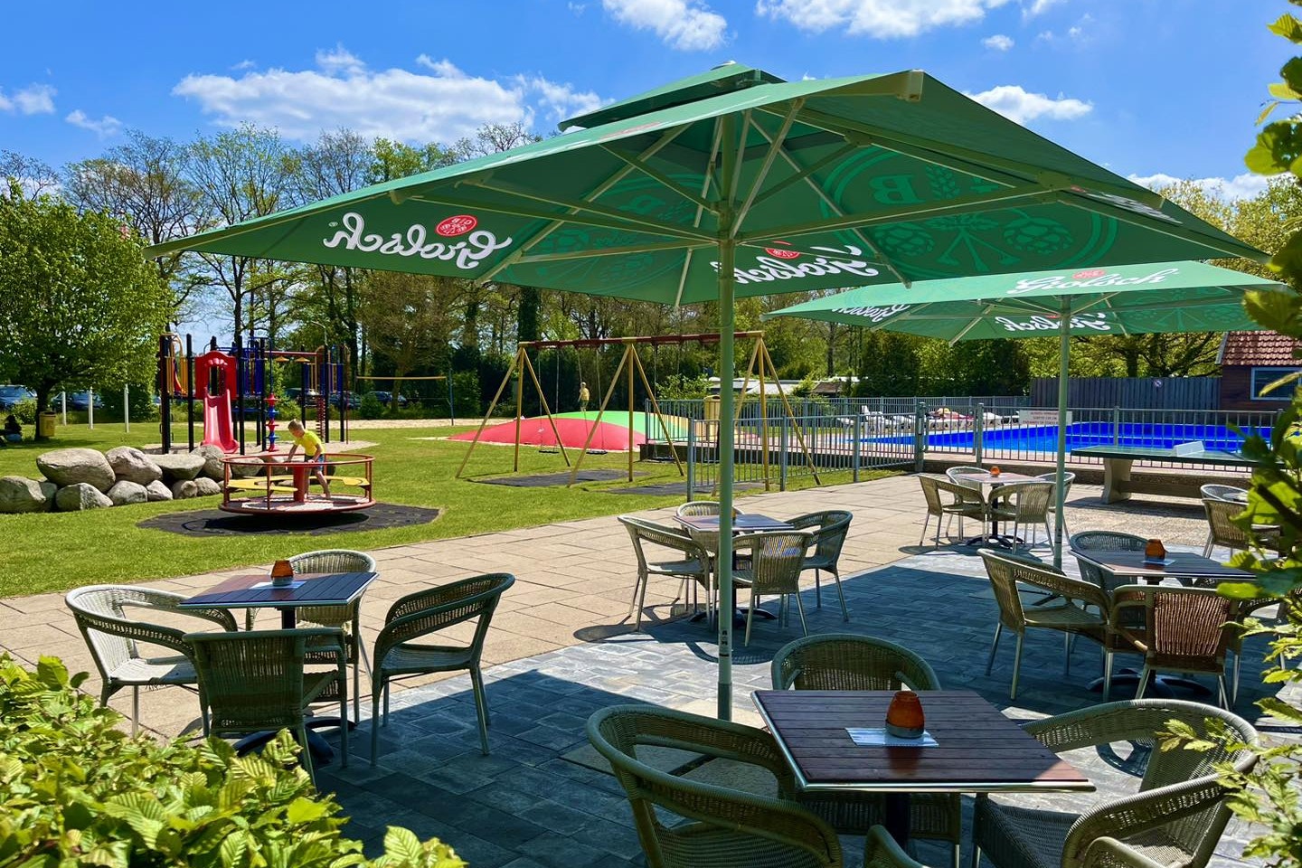 Camping De Haer - Terrasse neben Pool und Kinderspielplatz