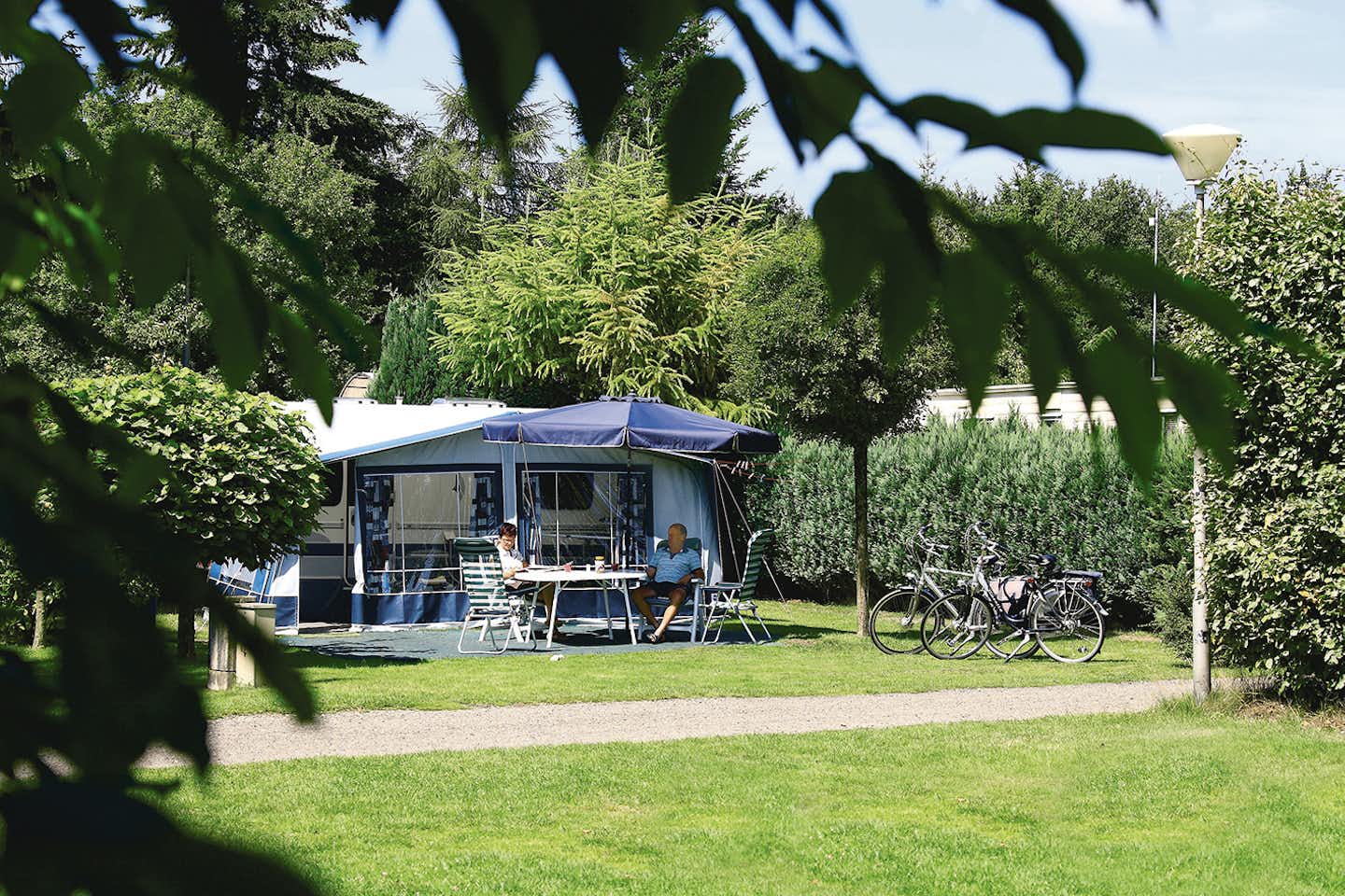 Camping De Holterberg - Camper sitzen vor dem Wohnmobil im Schatten der Markise