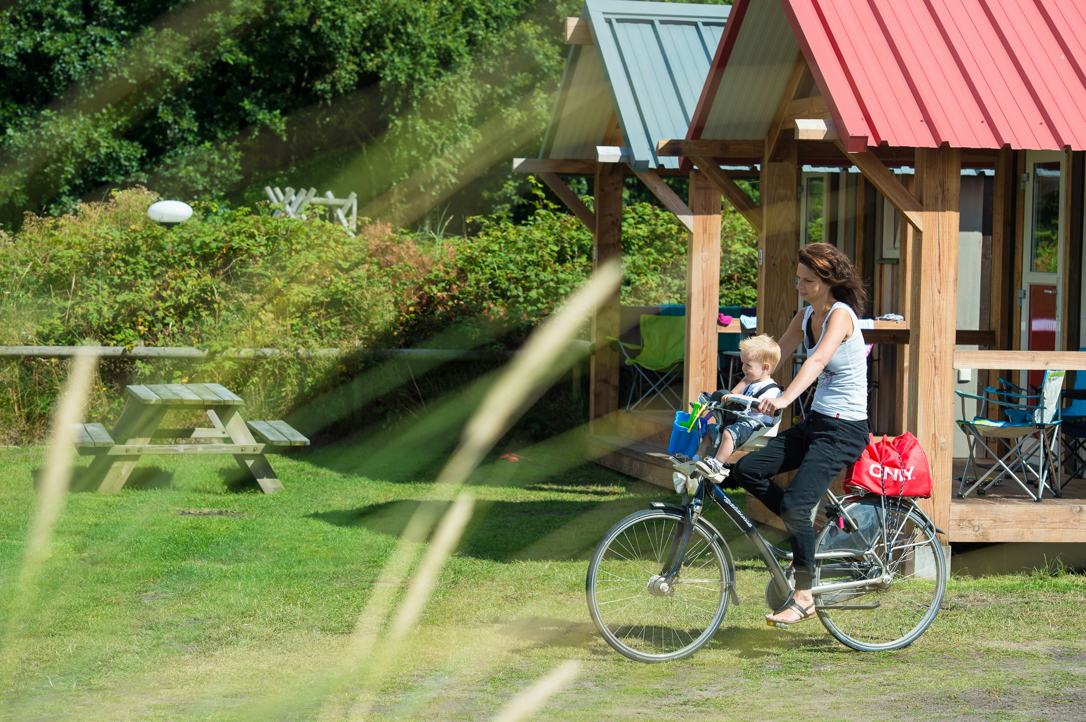 Camping De Kiekduun - Camperin mit Kind fährt Fahrrad auf dem Campingplatz