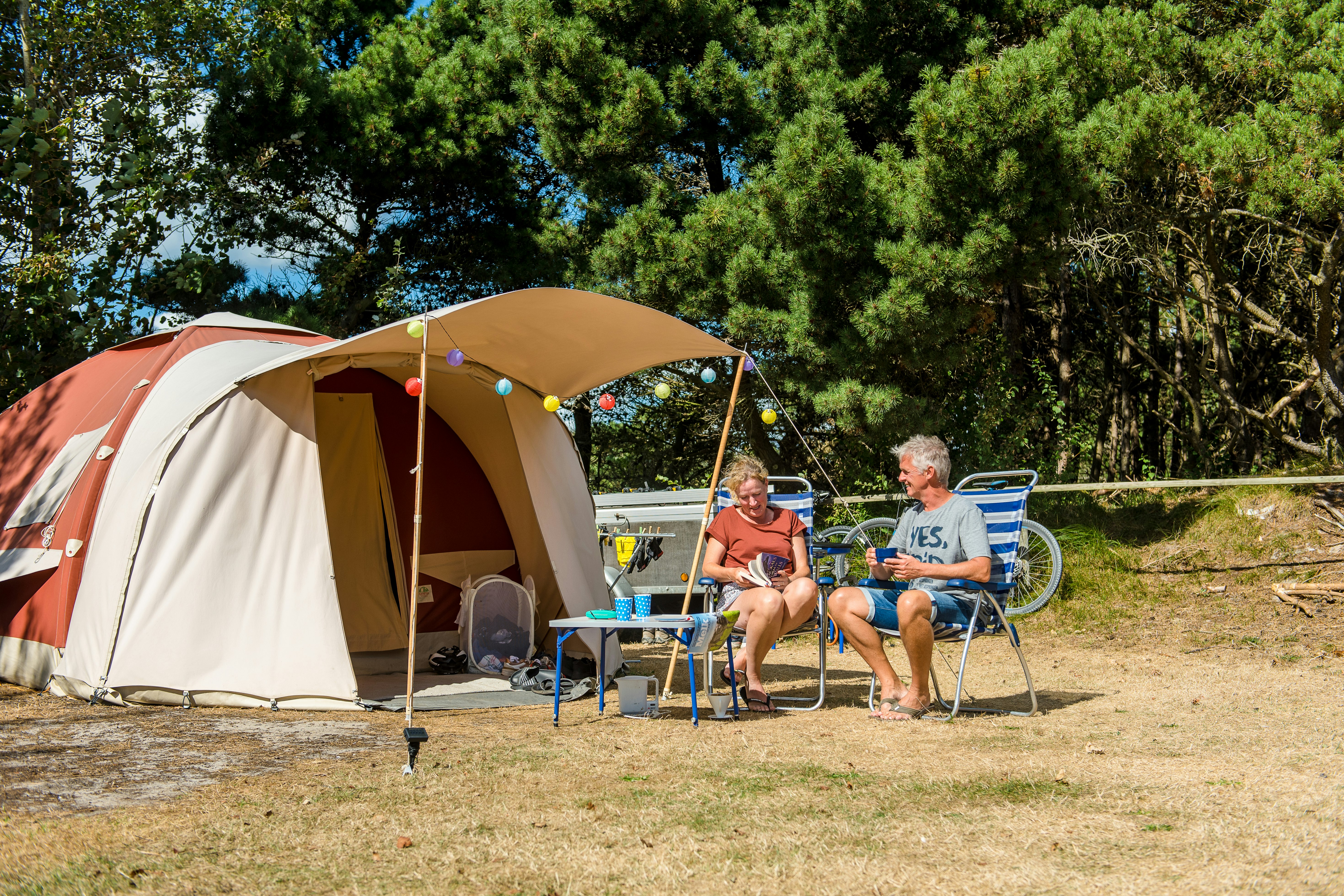 Camping De Kiekduun - Paar sitzt auf Campingstühlen vor ihrem Zeltplatz