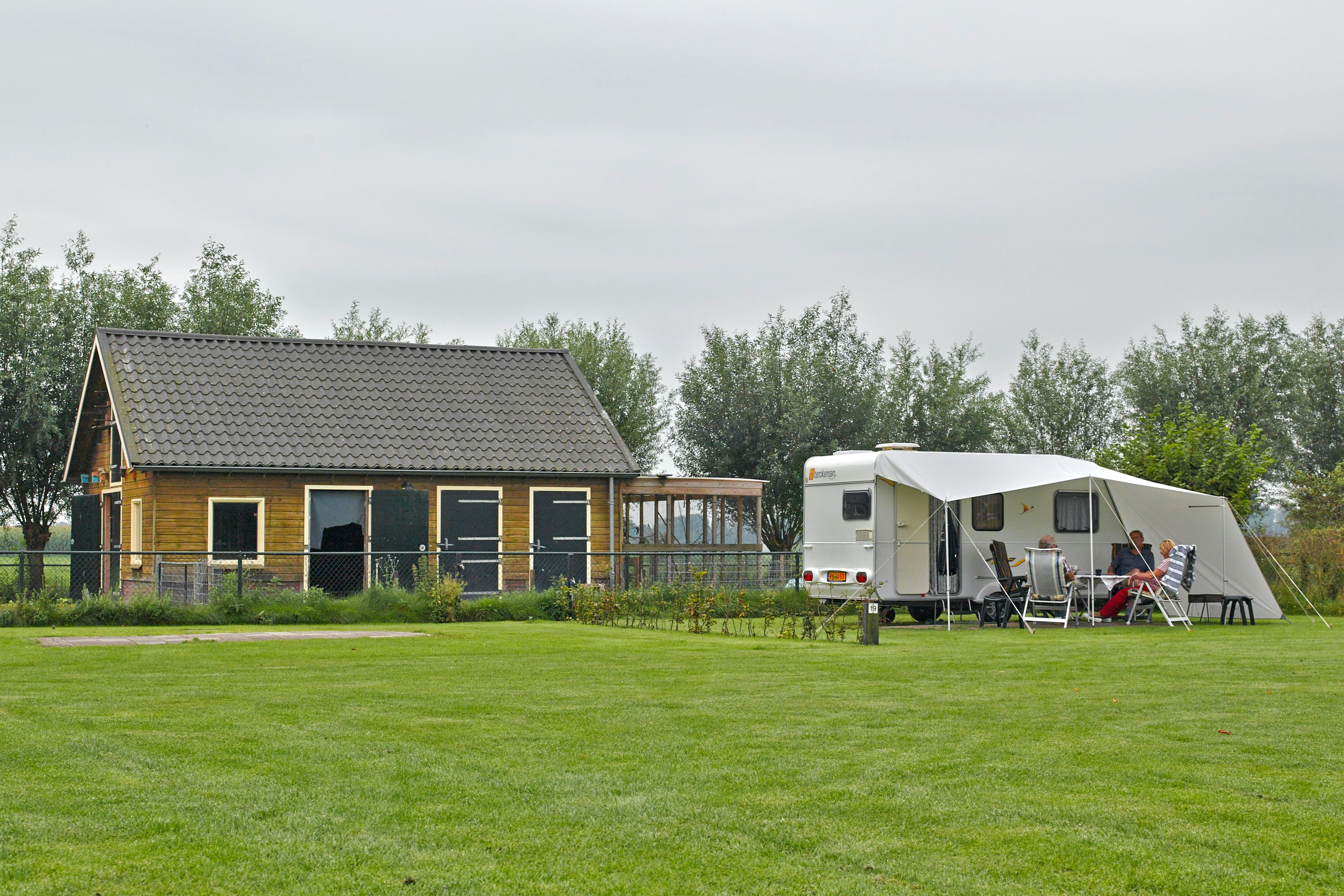 Camping De Kleine Weide - Wohnwagen auf Standplatz und Gebäude auf dem Campingplatz