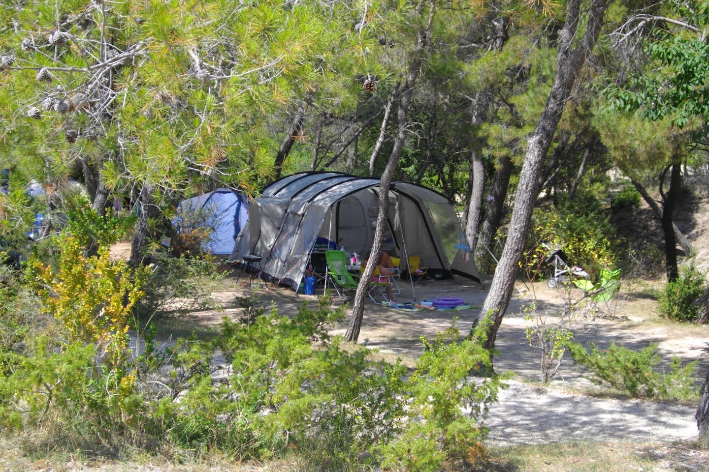 Camping de L' Ayguette - Zelte auf Stellplatz im Grünen mit sitzenden Campern
